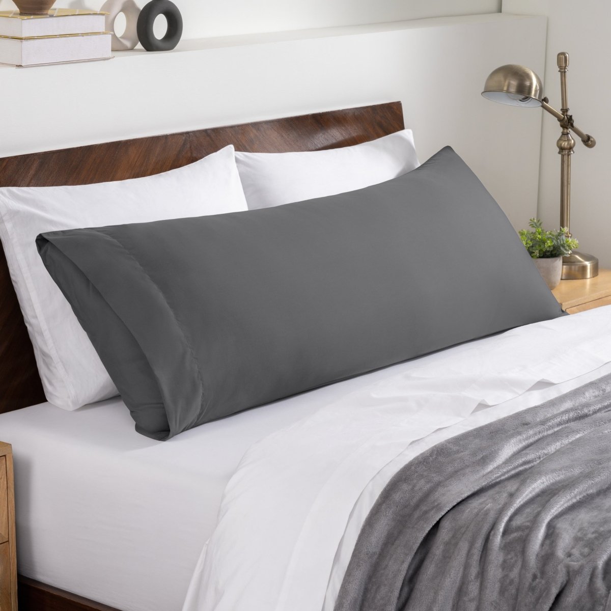 Bed sheets and pillows on a neatly made bed with a wooden headboard.