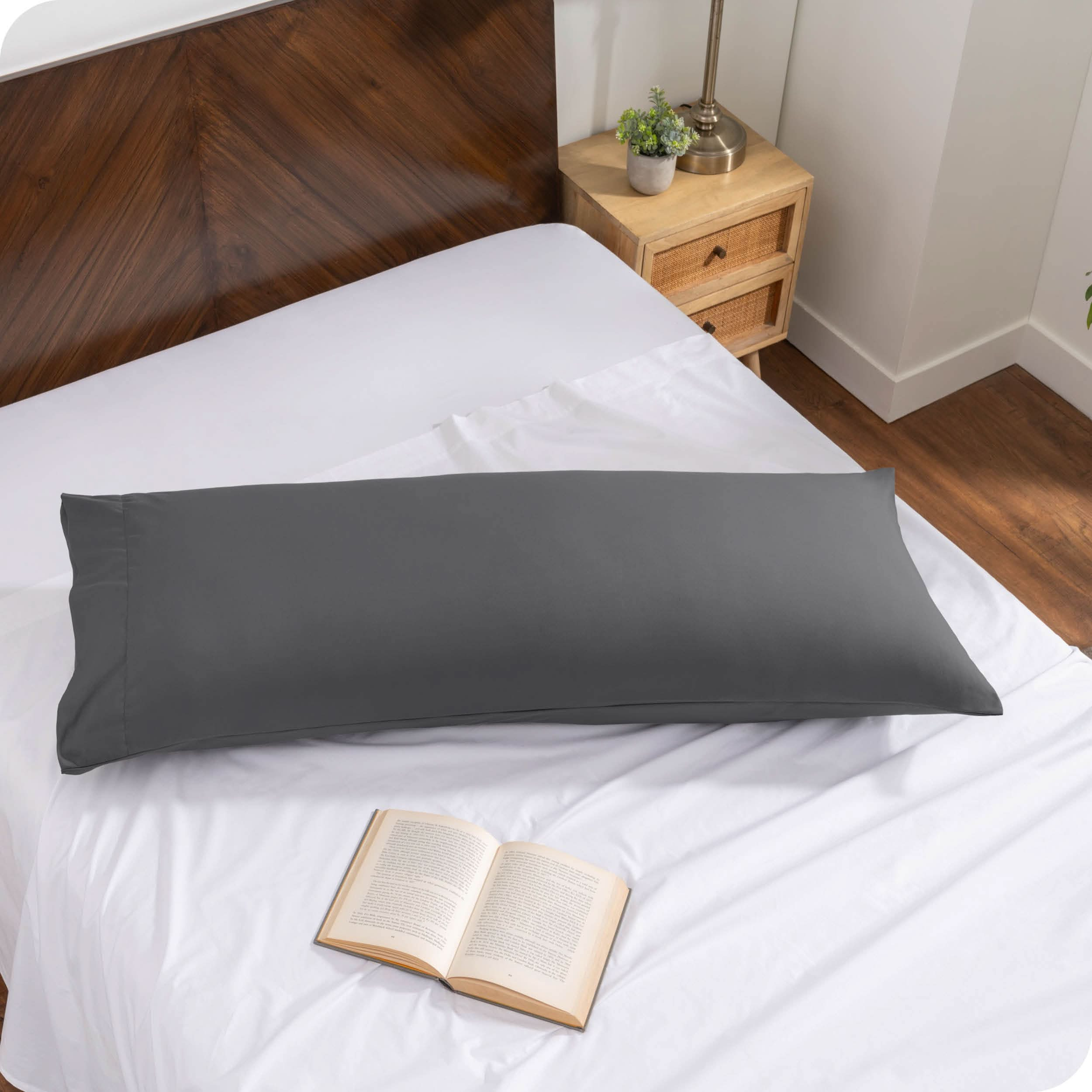 A body pillow cover on a pillow on a bed made with all white bedding