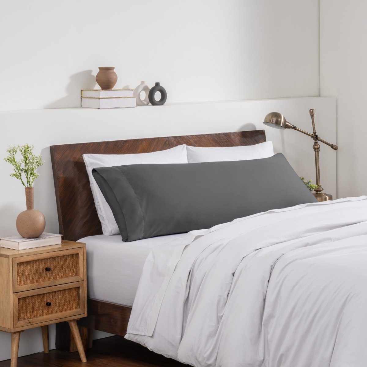 Bedroom with a wooden headboard and white bedding, featuring a nightstand and decorative items.