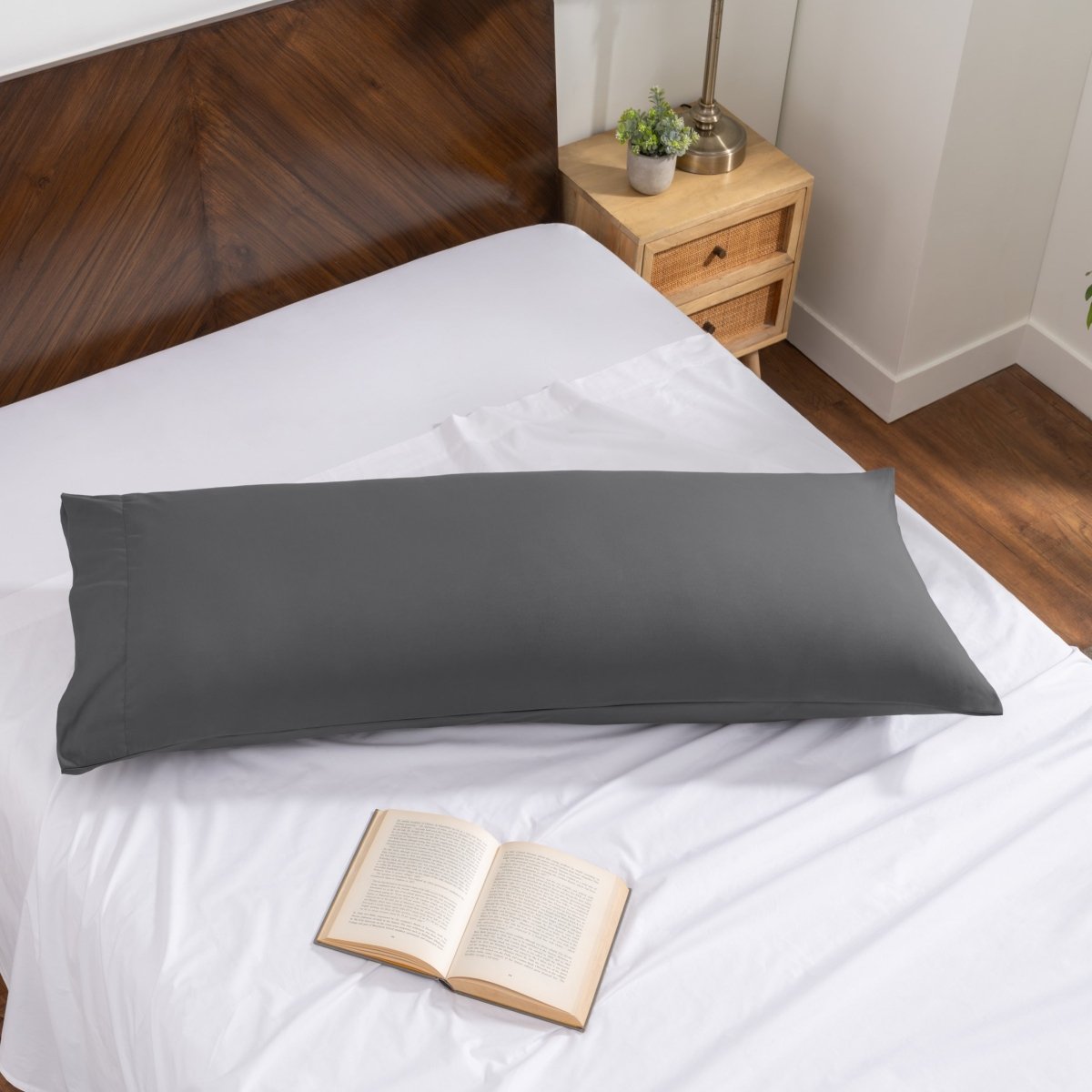 Pillowcase on a body pillow with a wooden headboard and plant in the background