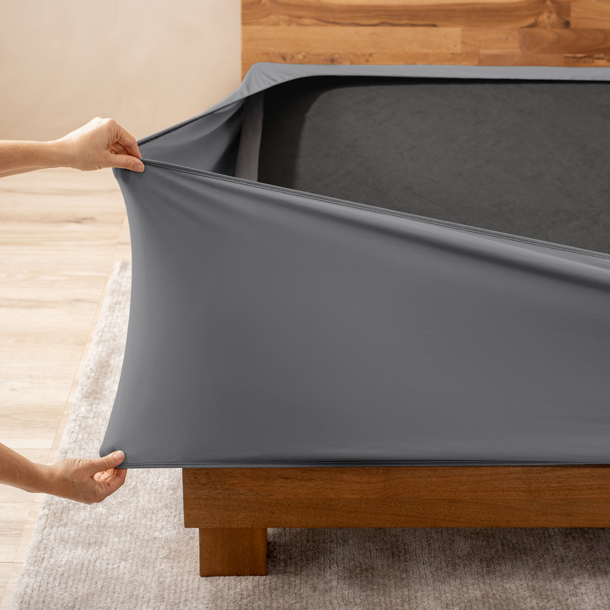 A person stretching a box spring cover