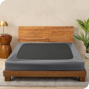 A cover on a box spring set on a wooden bed frame