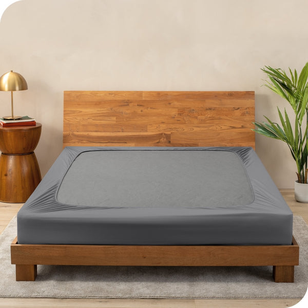 A cover on a box spring set on a wooden bed frame