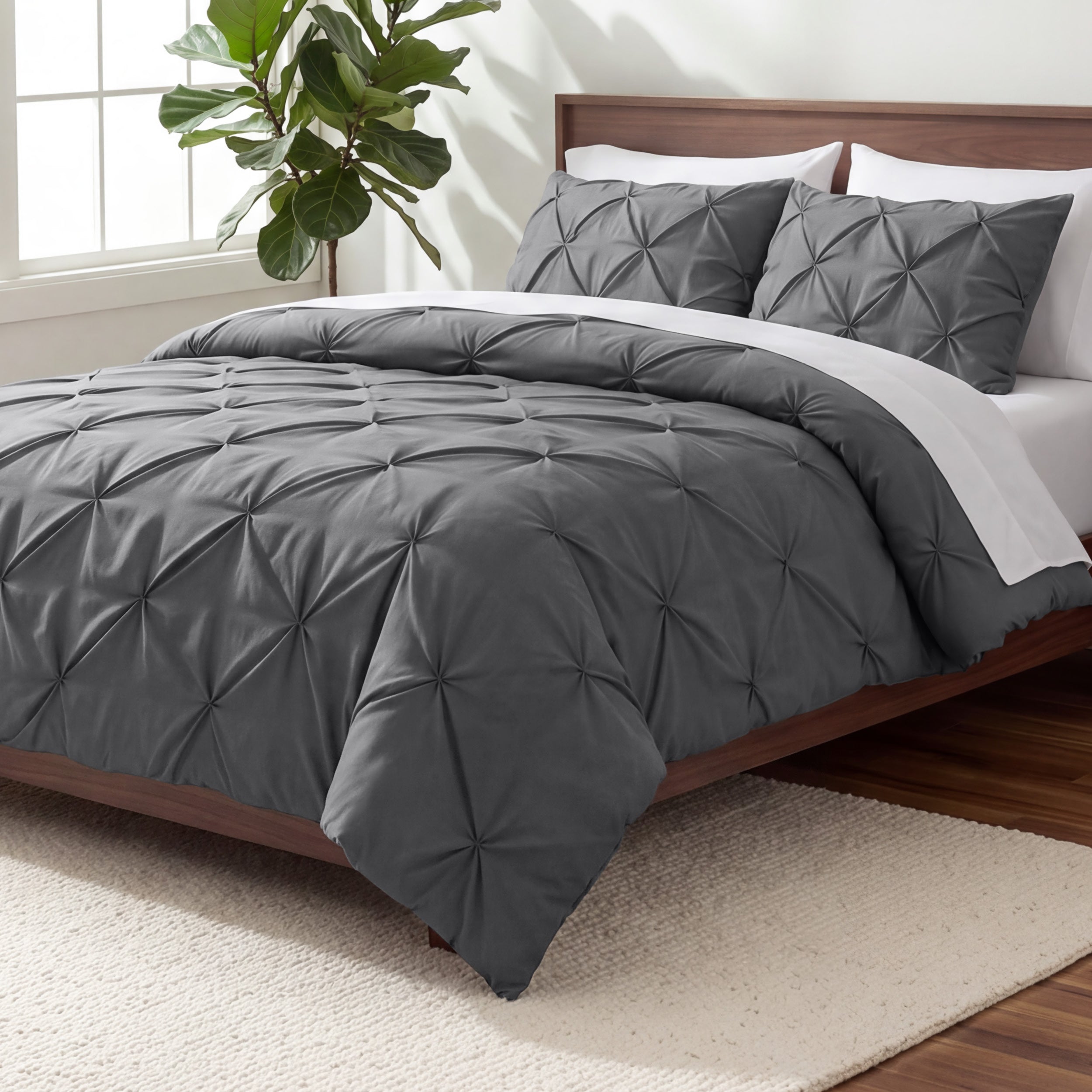 Gray pintuck comforter on a bed in a bedroom setting with a plant and nightstand.