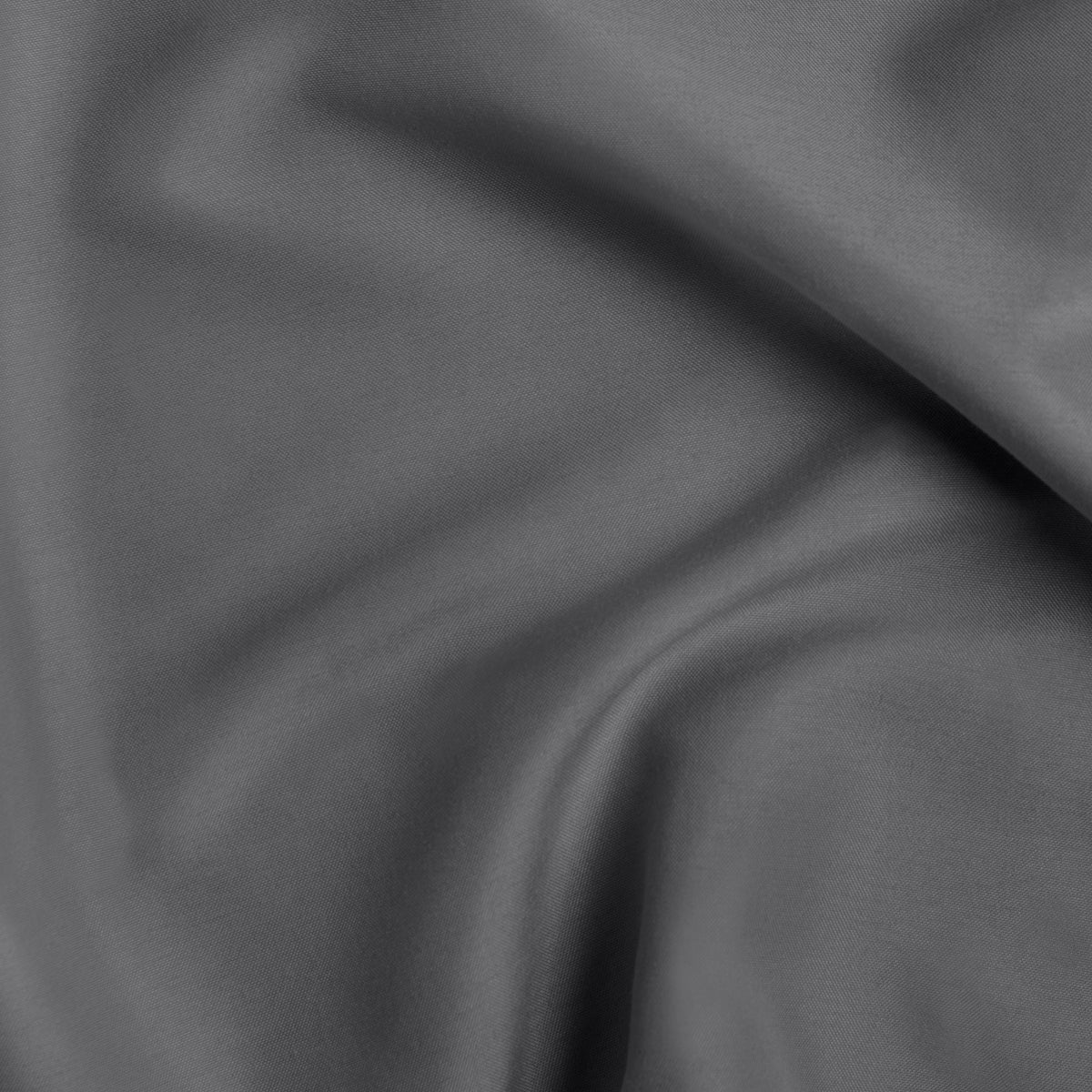 Gray pintuck comforter on a bed in a bedroom setting with a plant and nightstand.