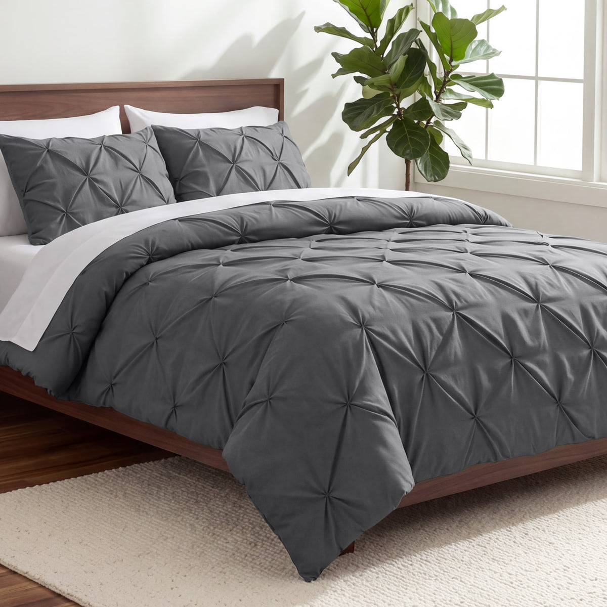 A gray pintuck comforter on a bed with matching pillow shams