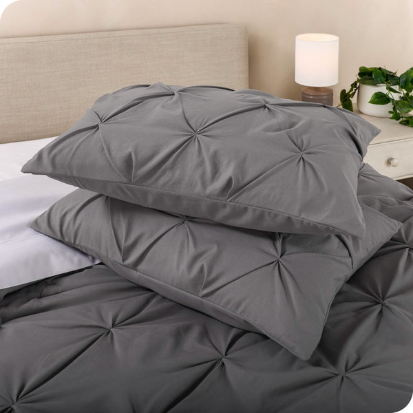 Two pillow shams with pillows inside stacked on a bed with a matching comforter