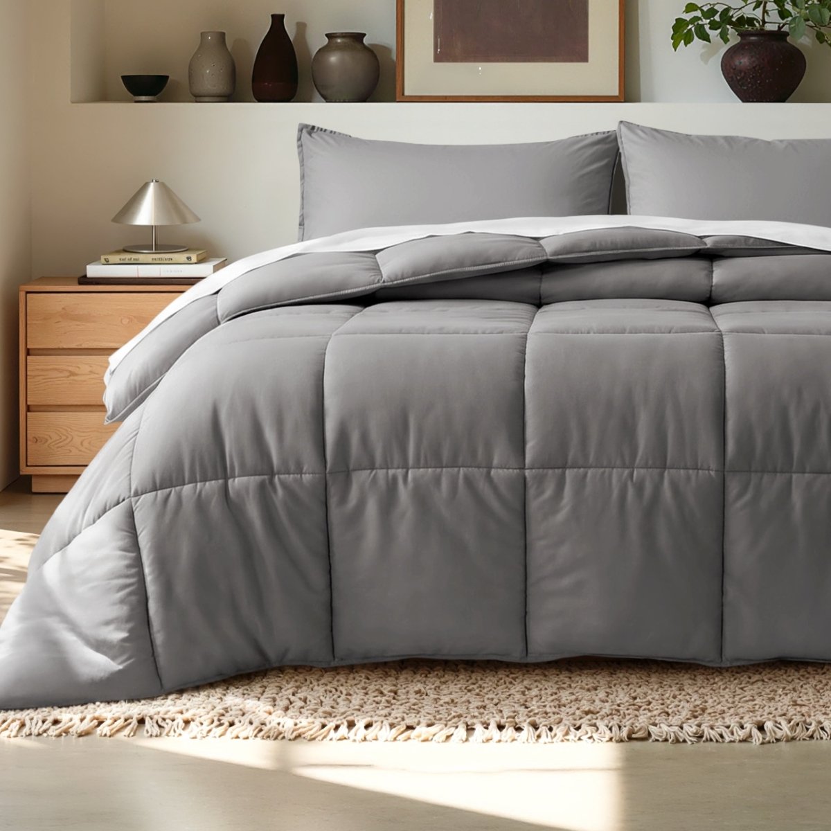 Comforter on a bed in a bedroom setting with a wooden nightstand and decorative items.