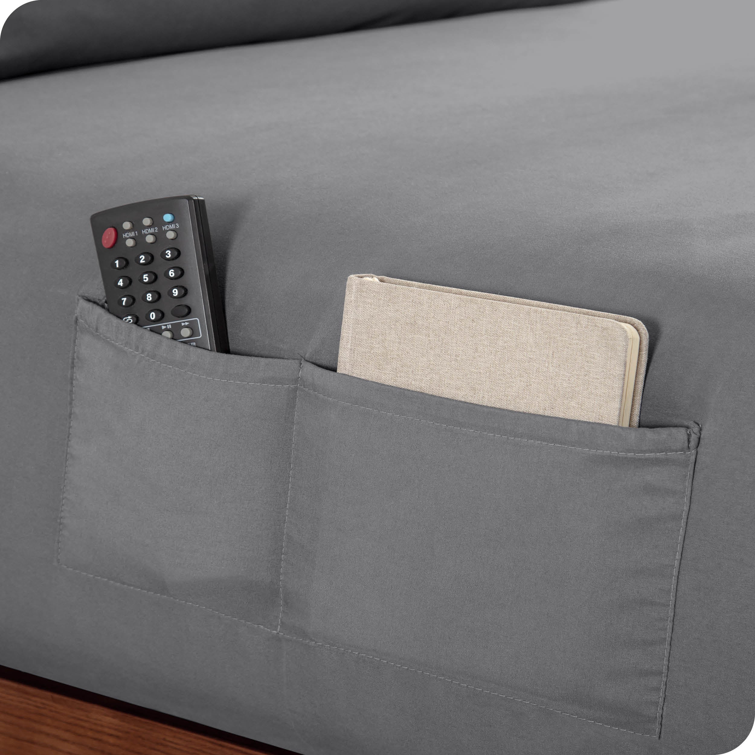 Close up of side pockets on a fitted sheet holding a remote and notebook