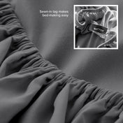 Gray fitted sheet with a sewn-in tag on a bed, showing close-up of the tag.