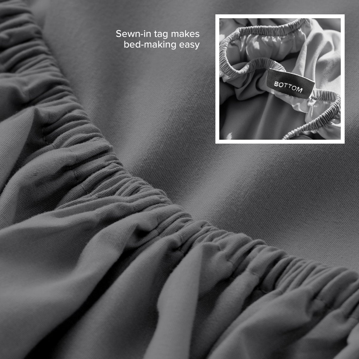 Gray fitted sheet with a sewn-in tag on a bed, showing close-up of the tag.