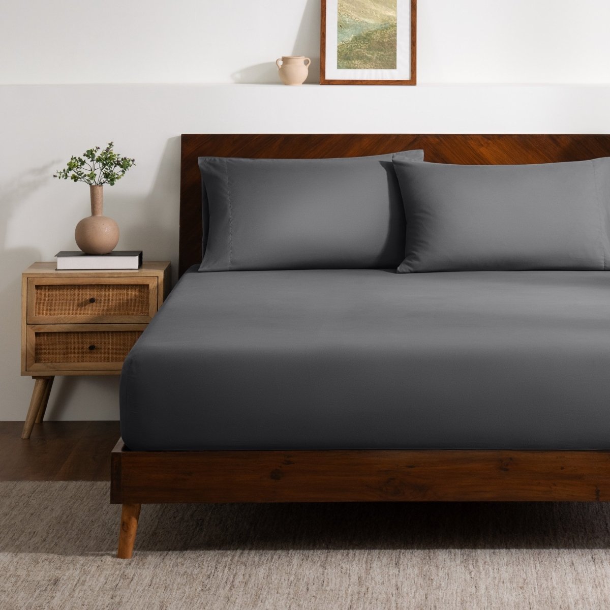 A bed made with a single fitted sheet and two matching pillowcases.