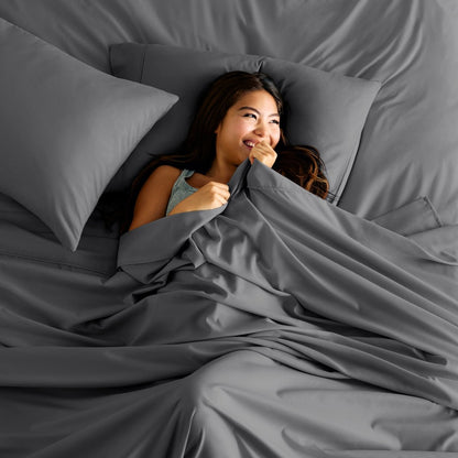 Woman lying in bed under a sheet smiling.