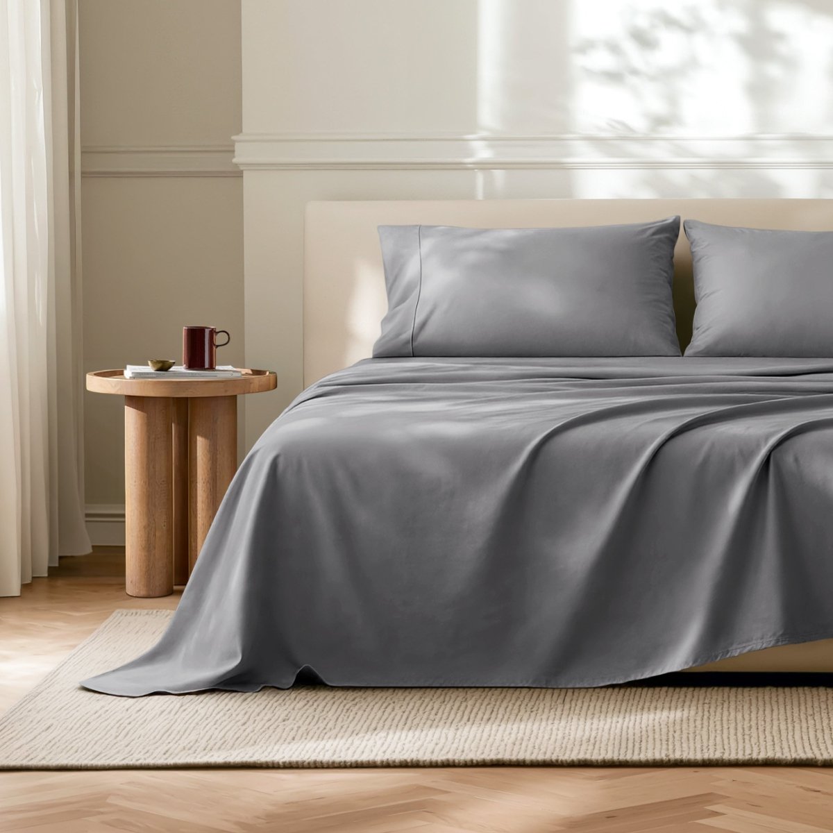 Microfiber flat sheet on a bed in a bedroom with a wooden side table.