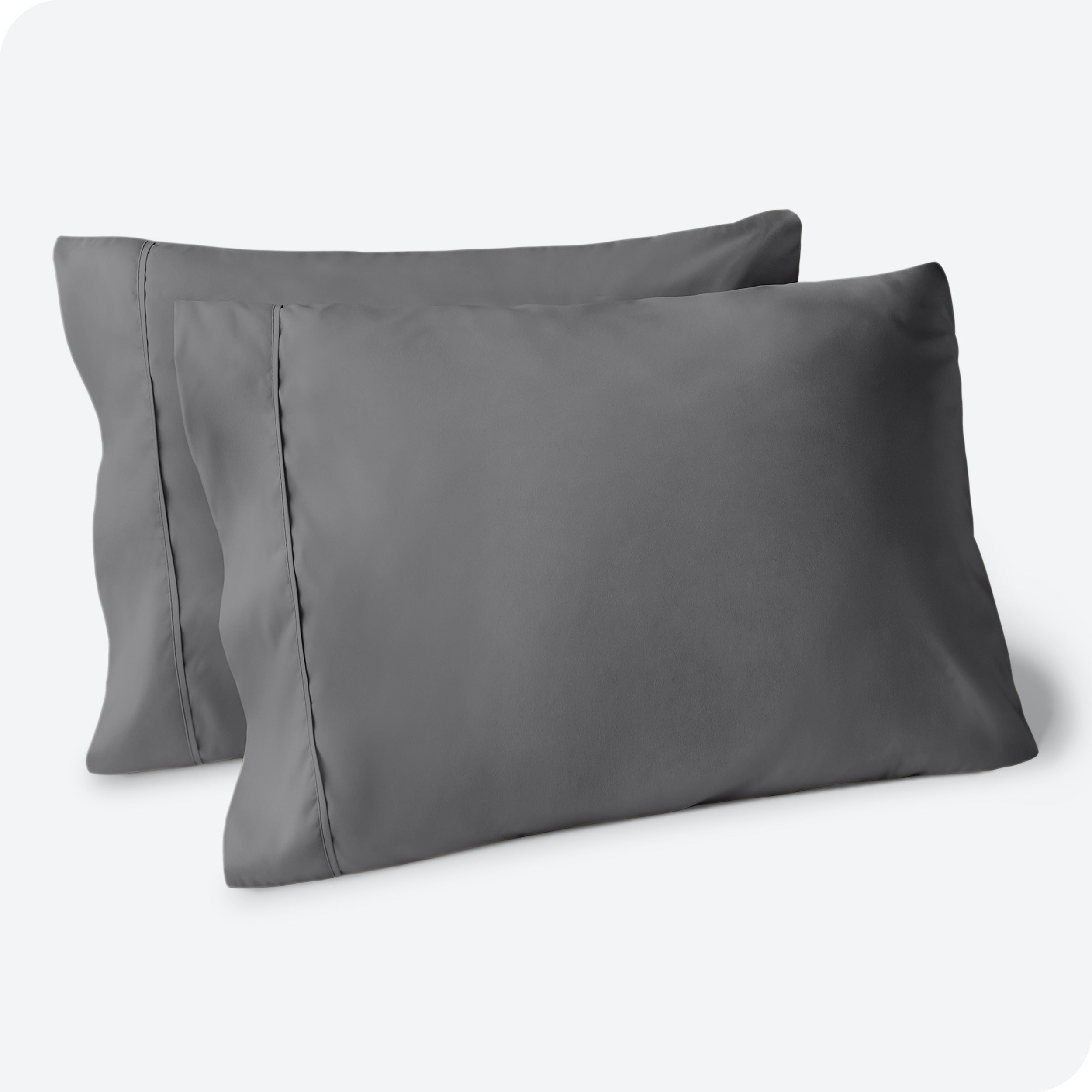Two pillows on a white background with grey pillowcases on them