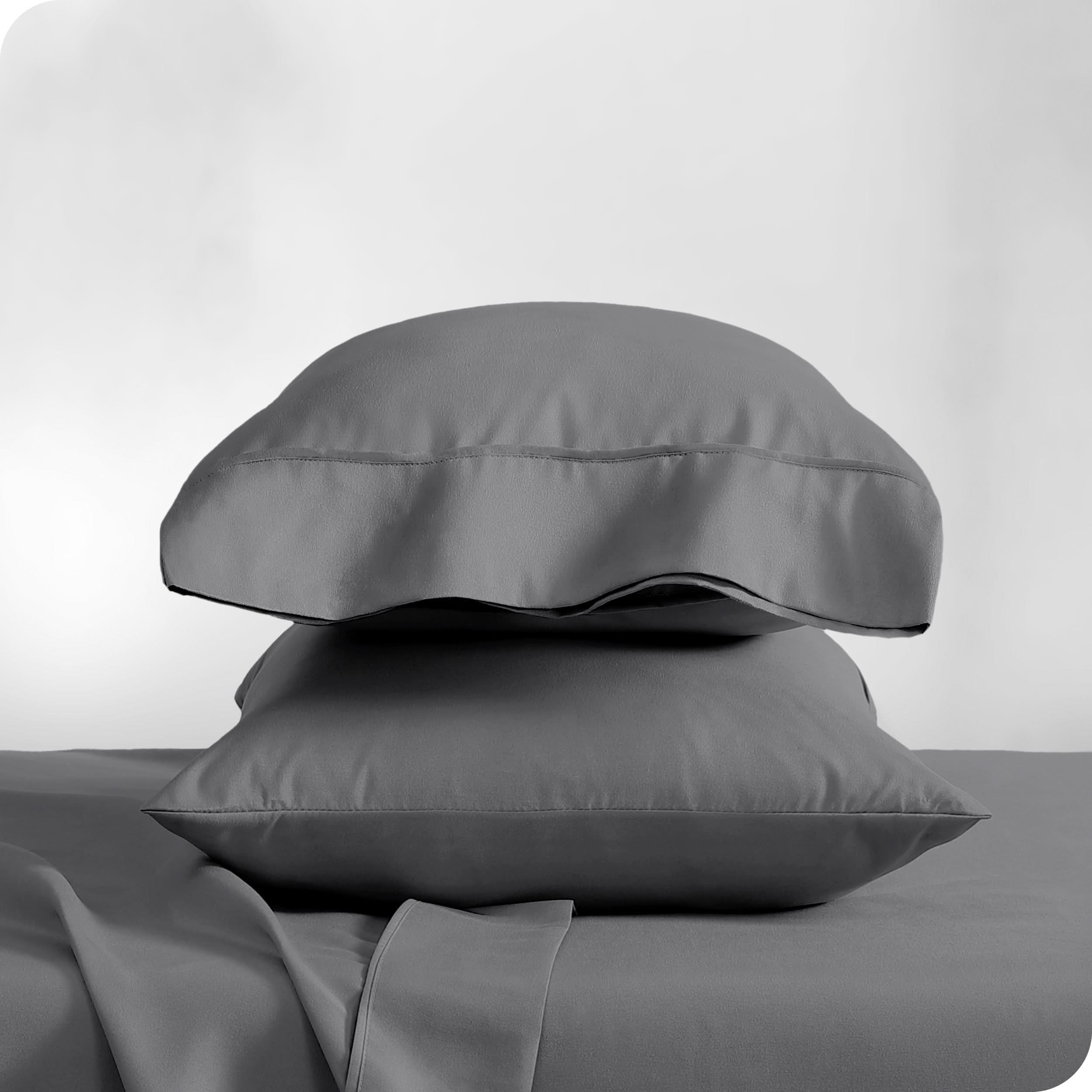 Two pillowcases on pillows stacked on a bed with matching sheets