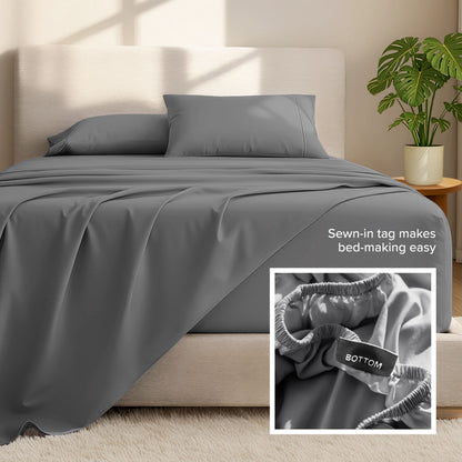 Bed sheets and pillows on a bed with a plant in the background