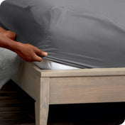 Person adjusting a fitted sheet on a mattress
