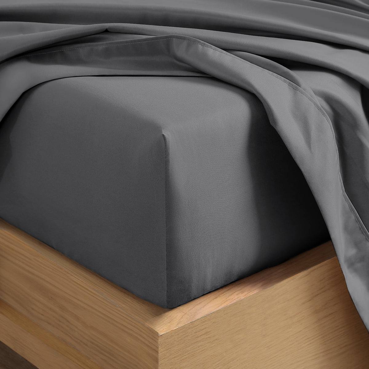 Close up of the corner of a mattress with a fitted sheet and flat sheet on it