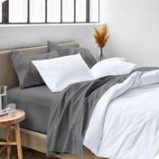A side view of a bed made with microfiber sheets and a white duvet cover
