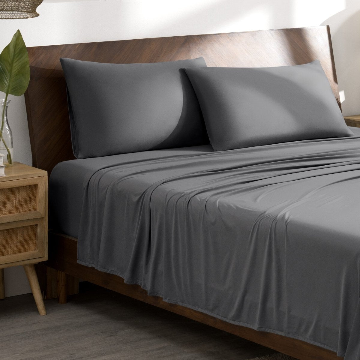 Microfiber stretch bed sheets and pillows on a wooden bed in a bedroom setting.