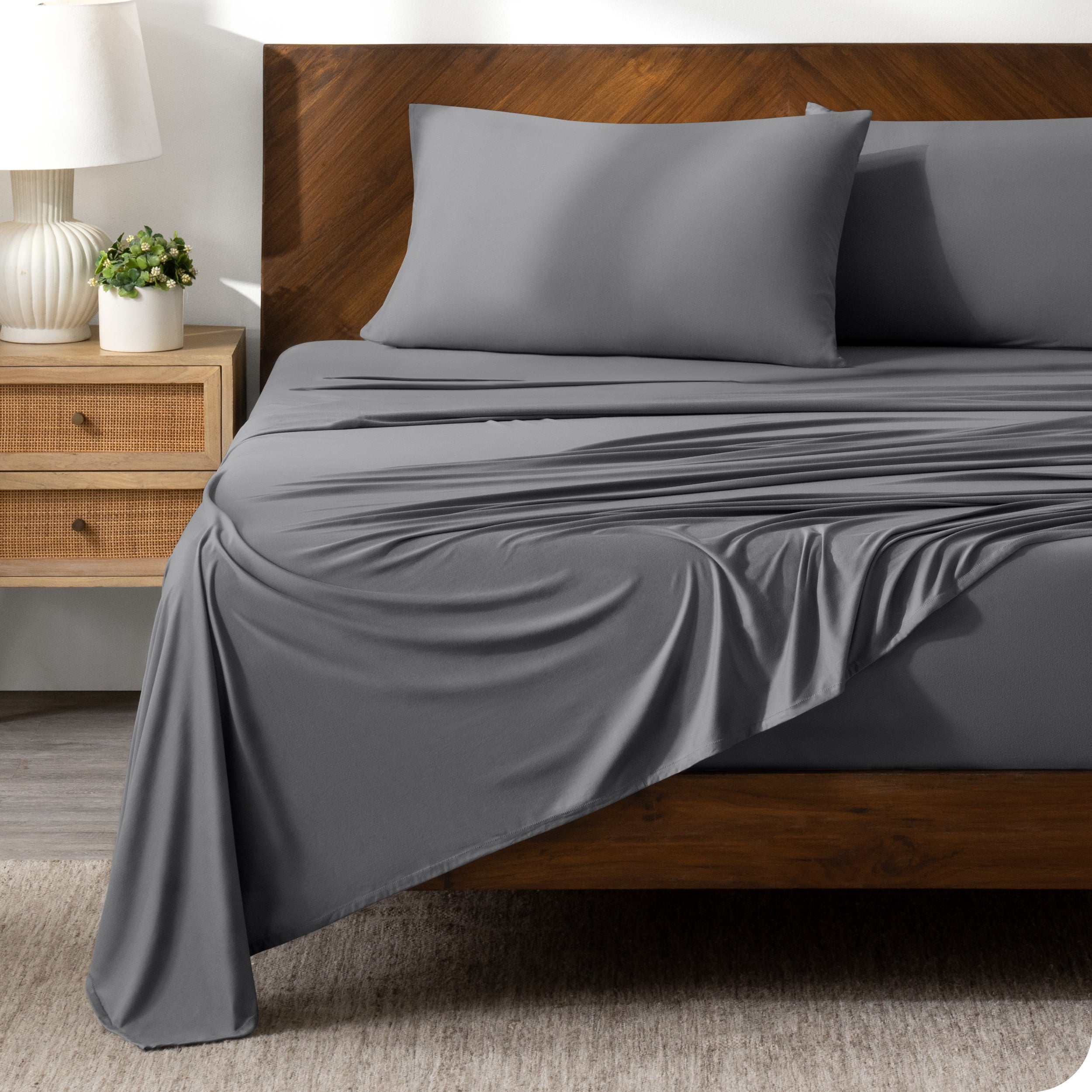 Grey sheet set on a bed with a dark wooden bed frame