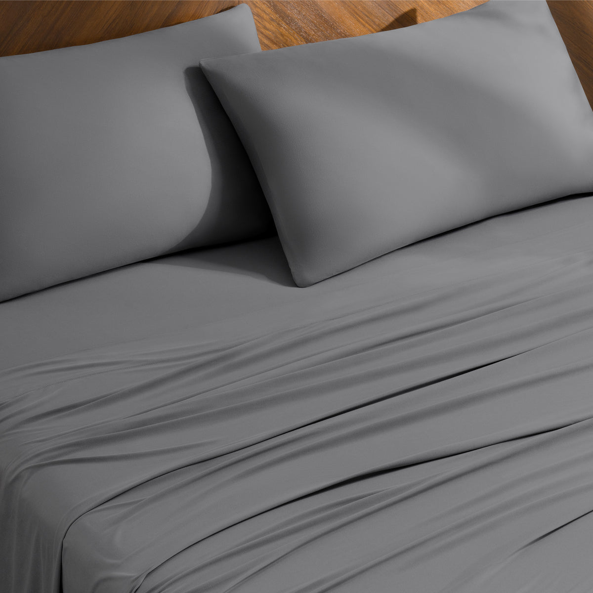 Bed sheets and pillowcases on a bed with a wooden headboard