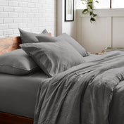 Bedding set on a bed with a white brick wall and window in the background