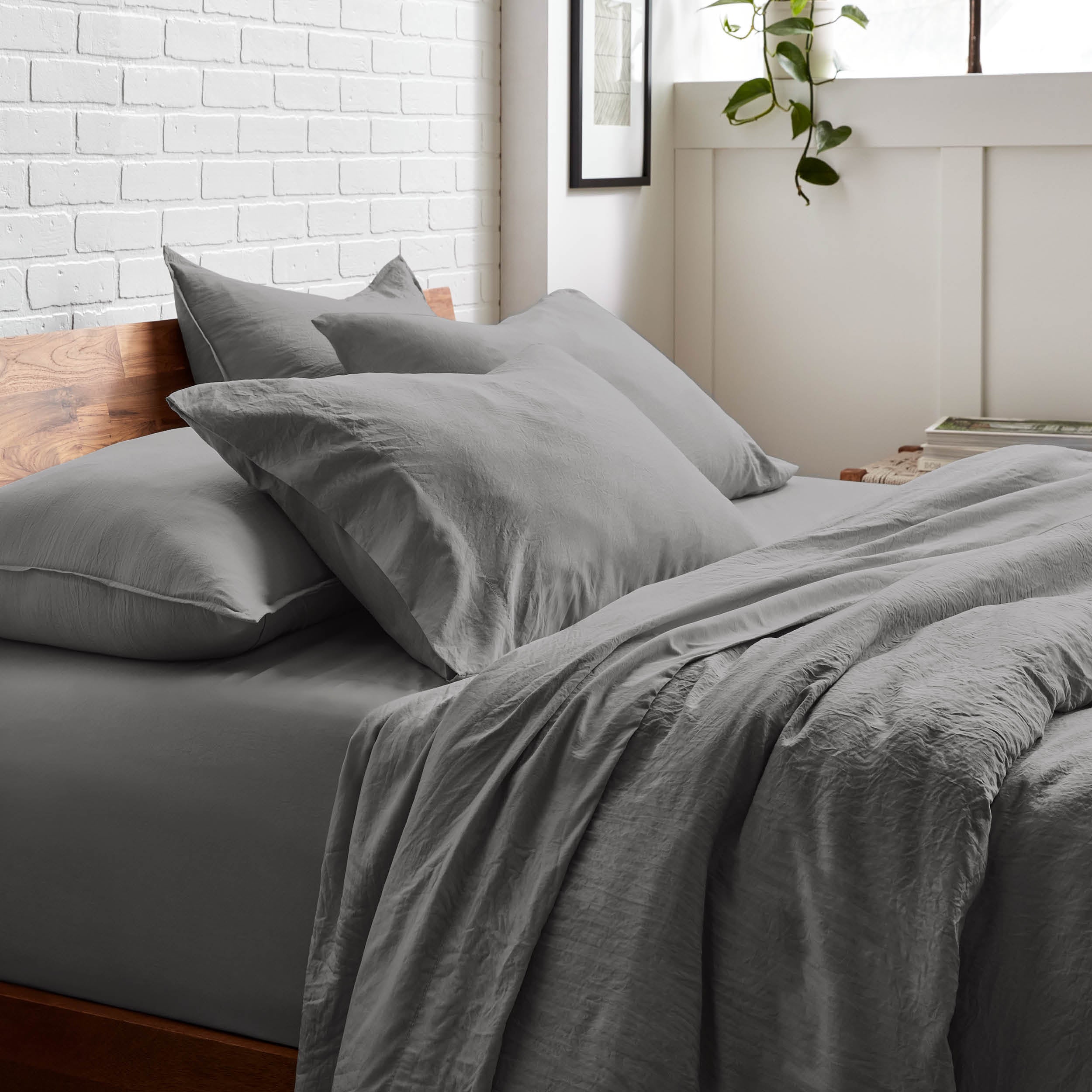 Bedding set on a bed with a white brick wall and window in the background