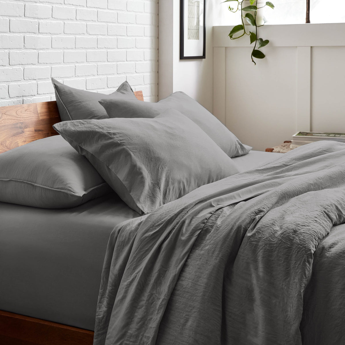Bedding set on a bed with a white brick wall and window in the background