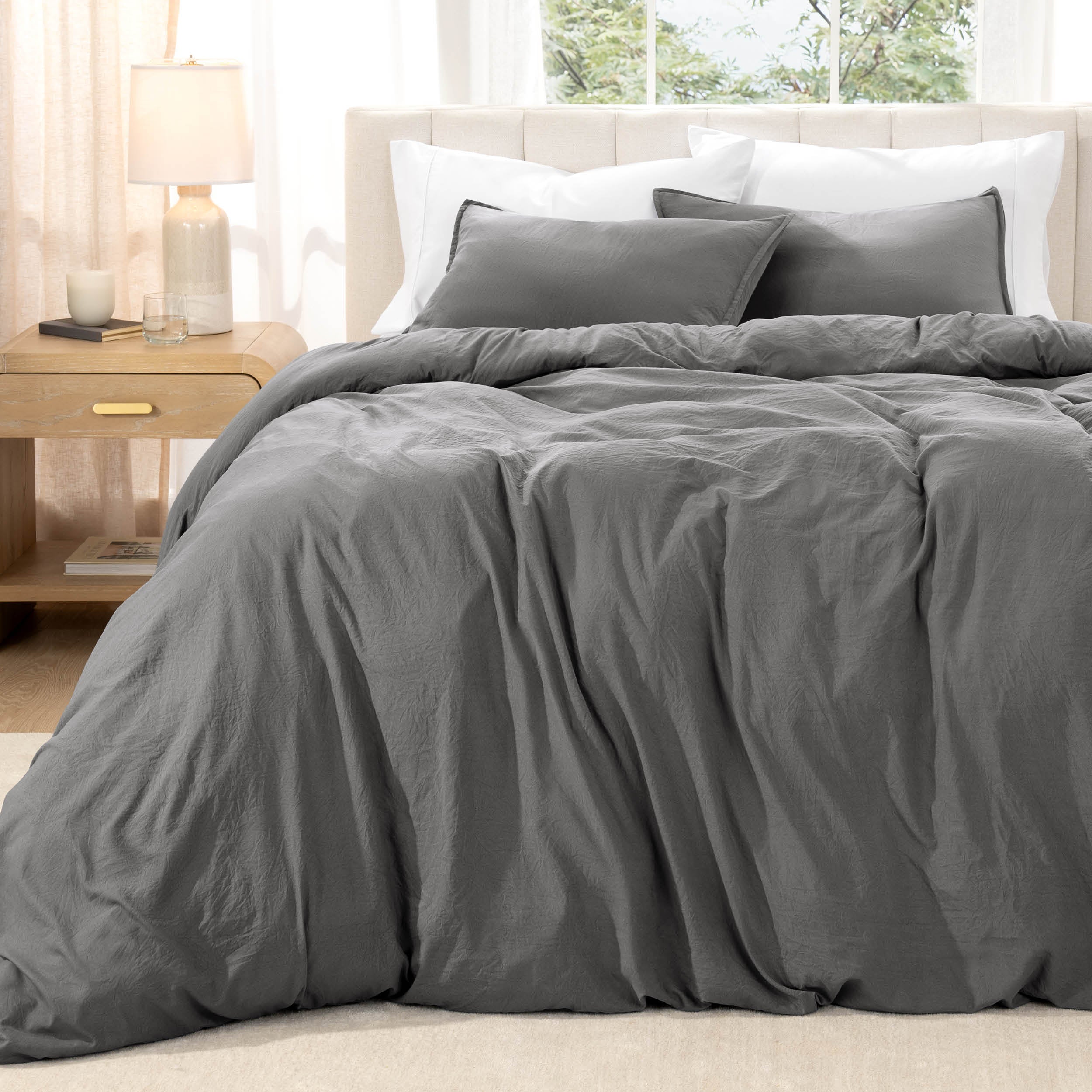 Bed with washed bedding and white pillows in a bright room