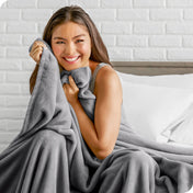 Woman sitting on a bed cuddling with a microplush blanket