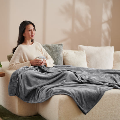 A woman sitting on a couch with a microplush blanket on her lap