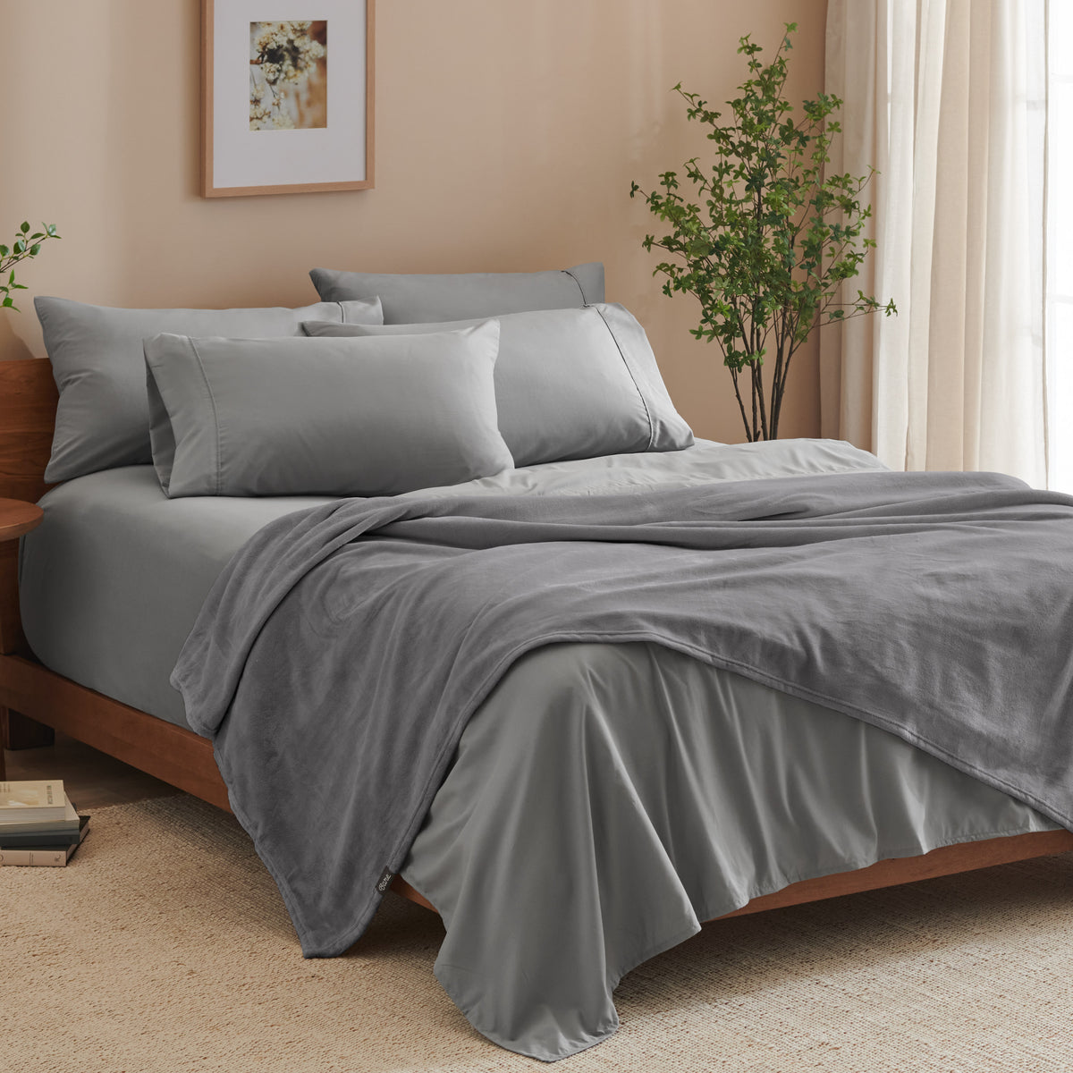 A bed made with grey sheets and a microplush blanket