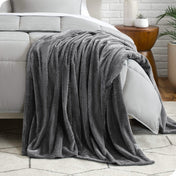 A microplush blanket is draped over the side and bottom of a neatly made bed.