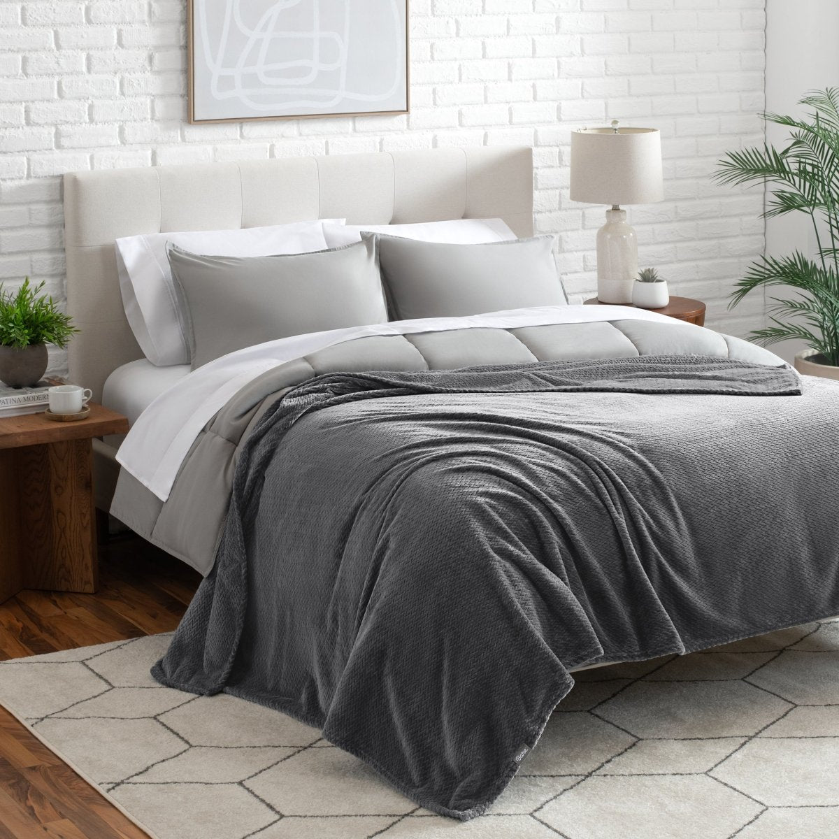 Neatly made bed with a blanket draped over the end of the bed