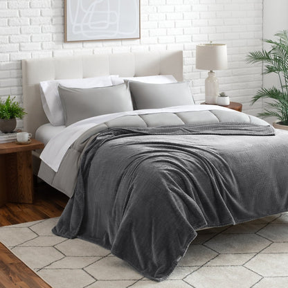Neatly made bed with a blanket draped over the end of the bed