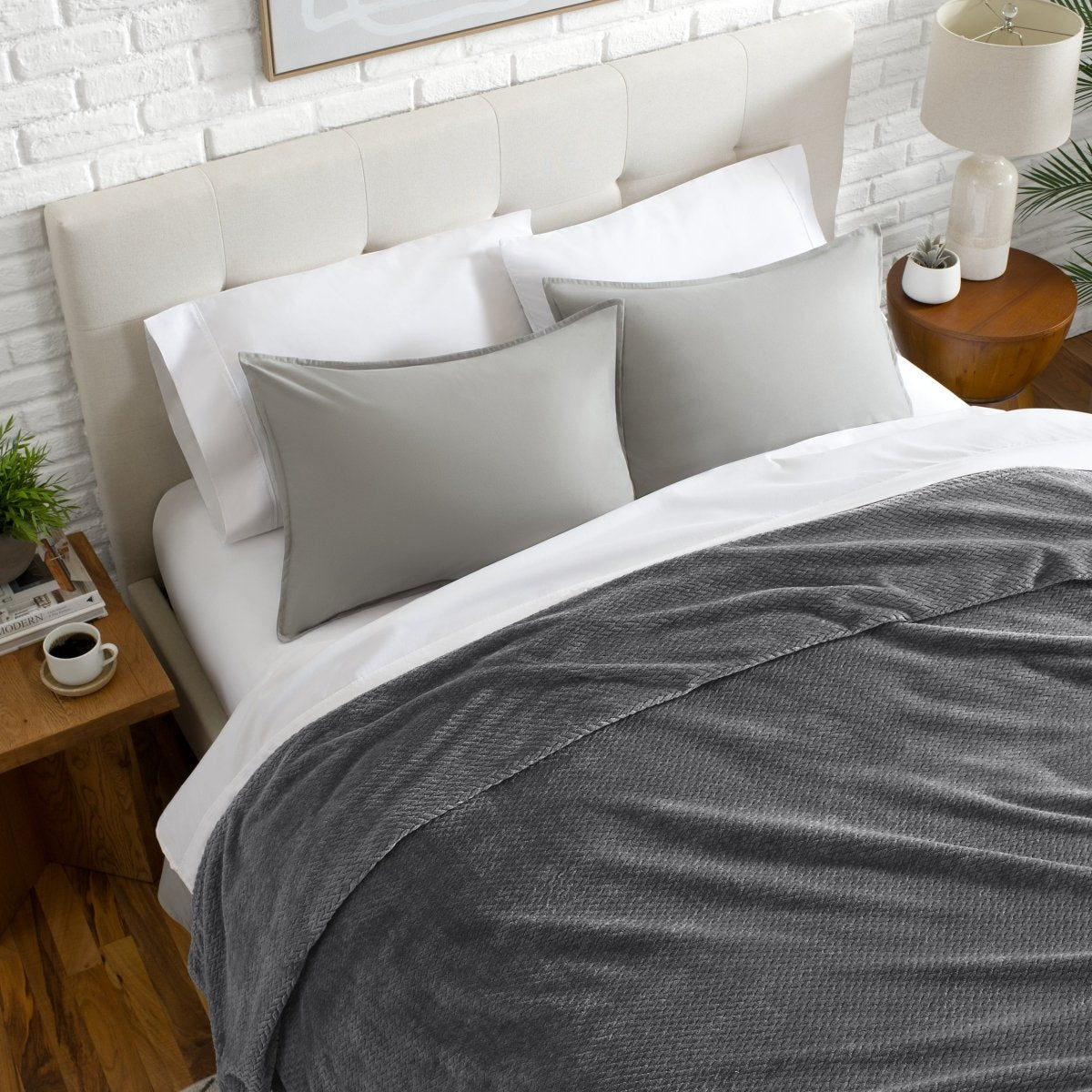 Neatly made bed with a chevron blanket over the comforter