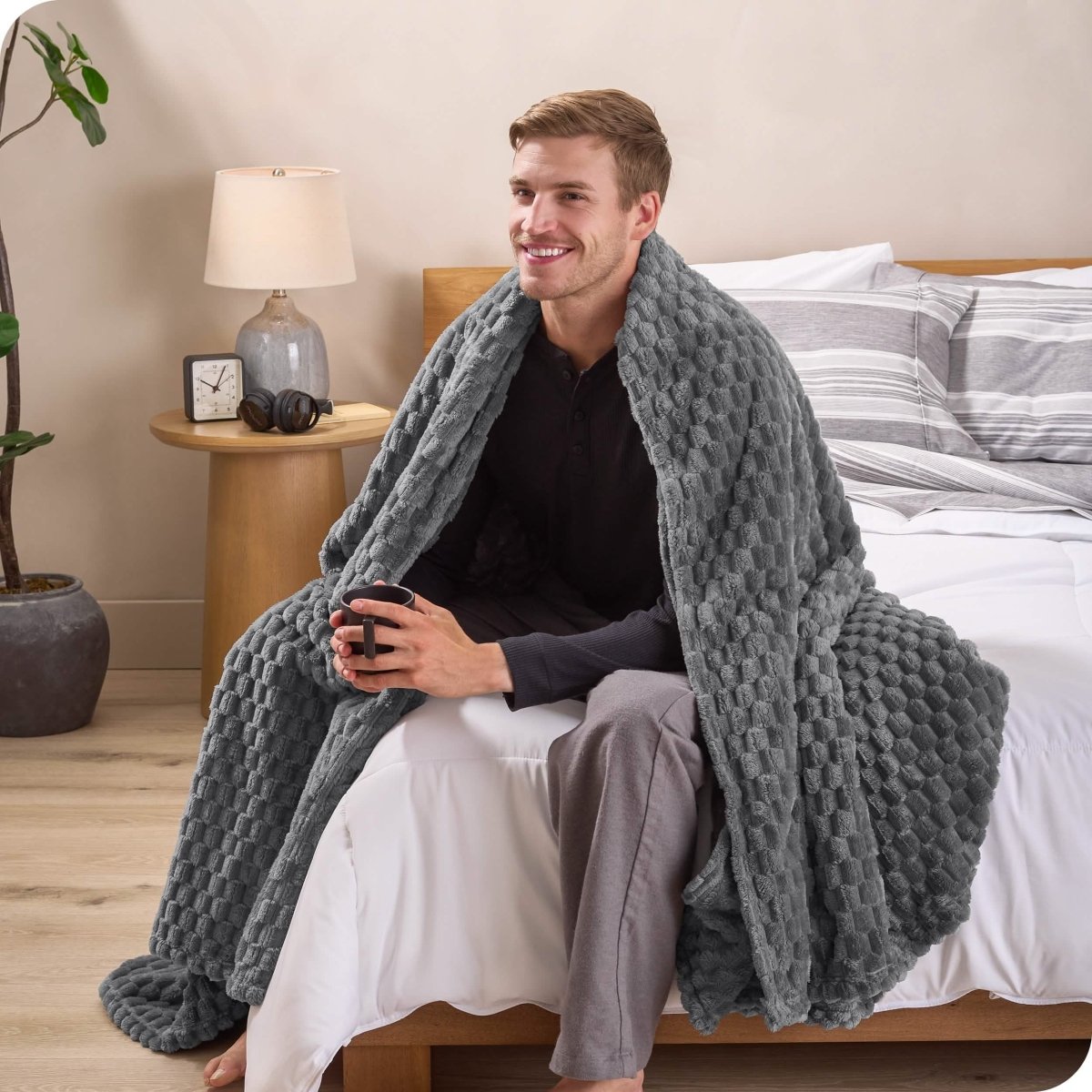 A man sitting on a bed wrapped in a microplush blanket
