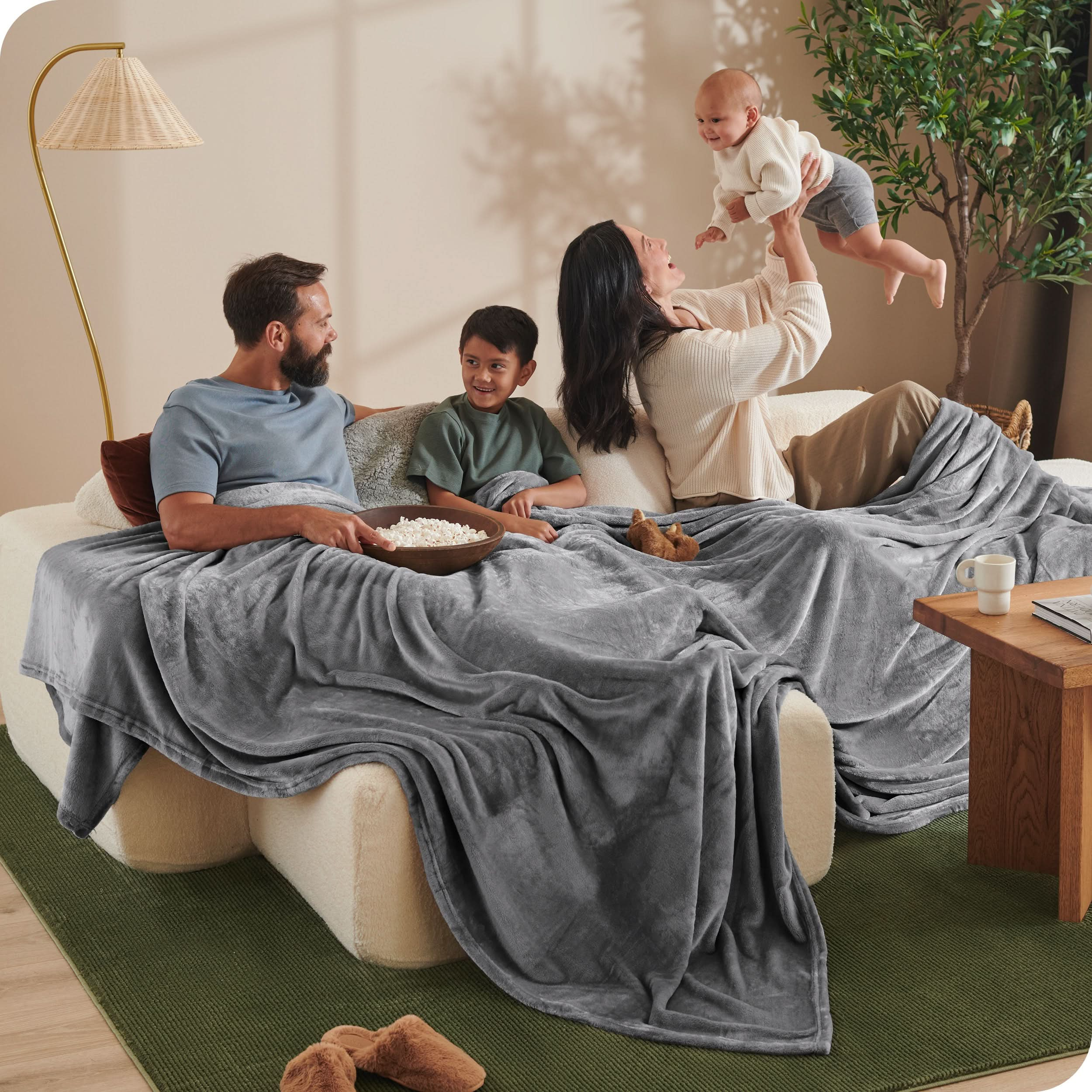 A family sitting with a giant microplush blanket covering them