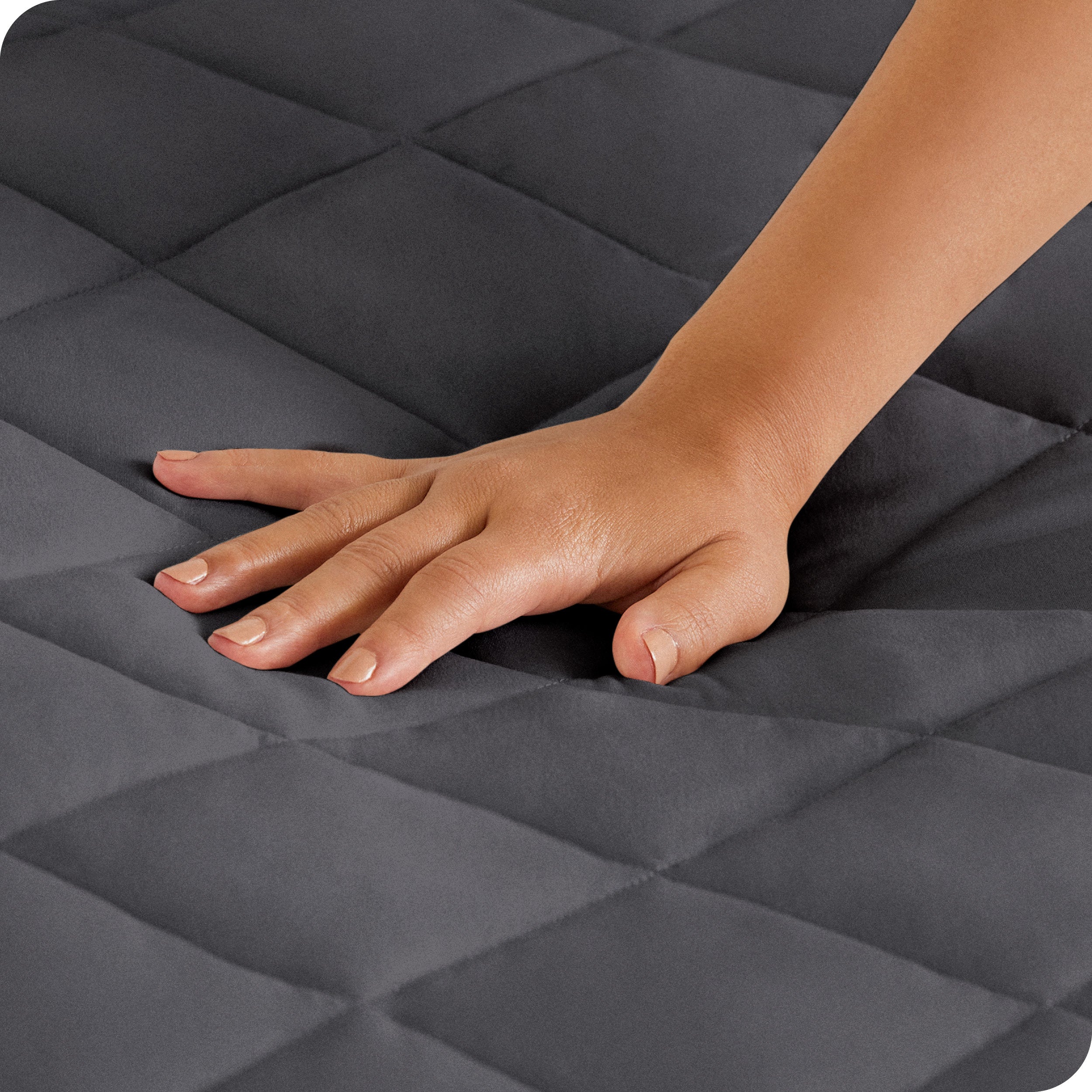 Close up of a woman's hand pressing down on a mattress pad