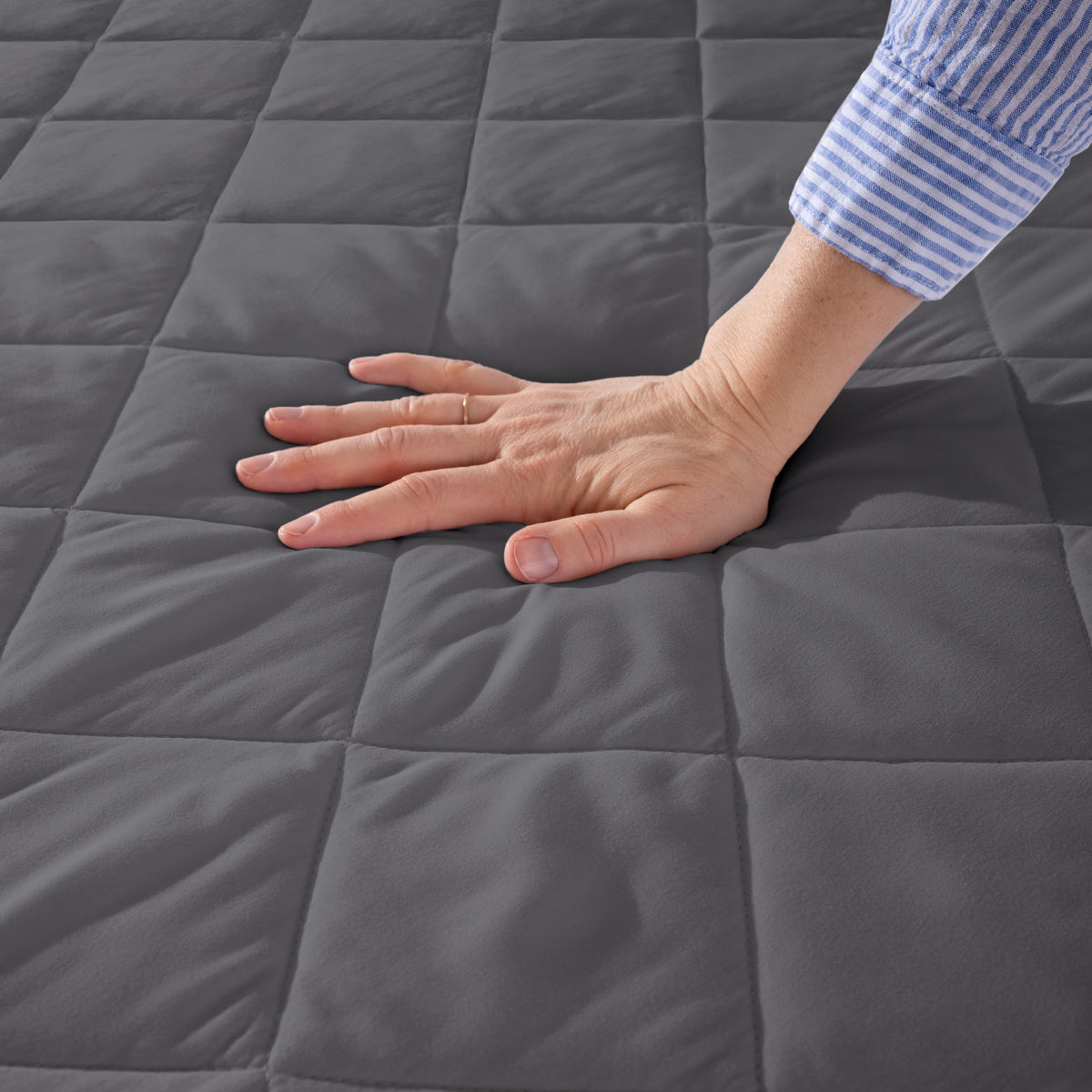 Hand touching a quilted mattress pad.
