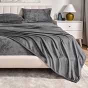 Microplush sheet set on a bed in a bedroom setting with a nightstand and lamp.
