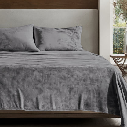 Microplush sheet set on a bed in a bedroom setting with a nightstand and lamp.