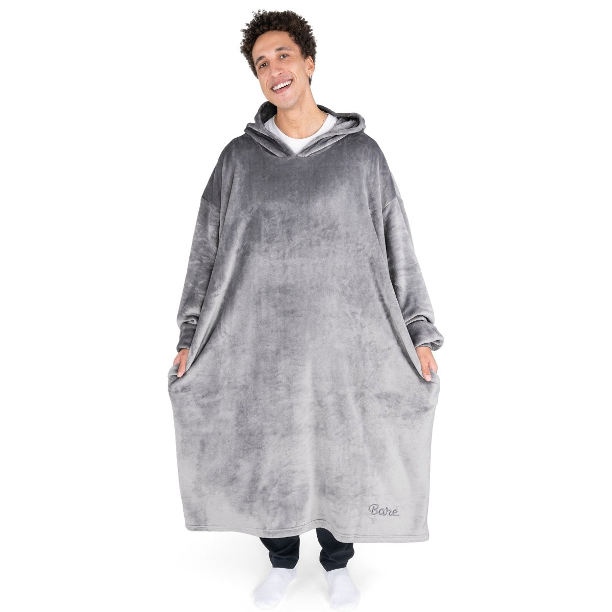 An adult is standing while wearing a long microplush wearable blanket