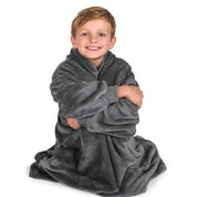 A boy is sitting while in a microplush wearable blanket.