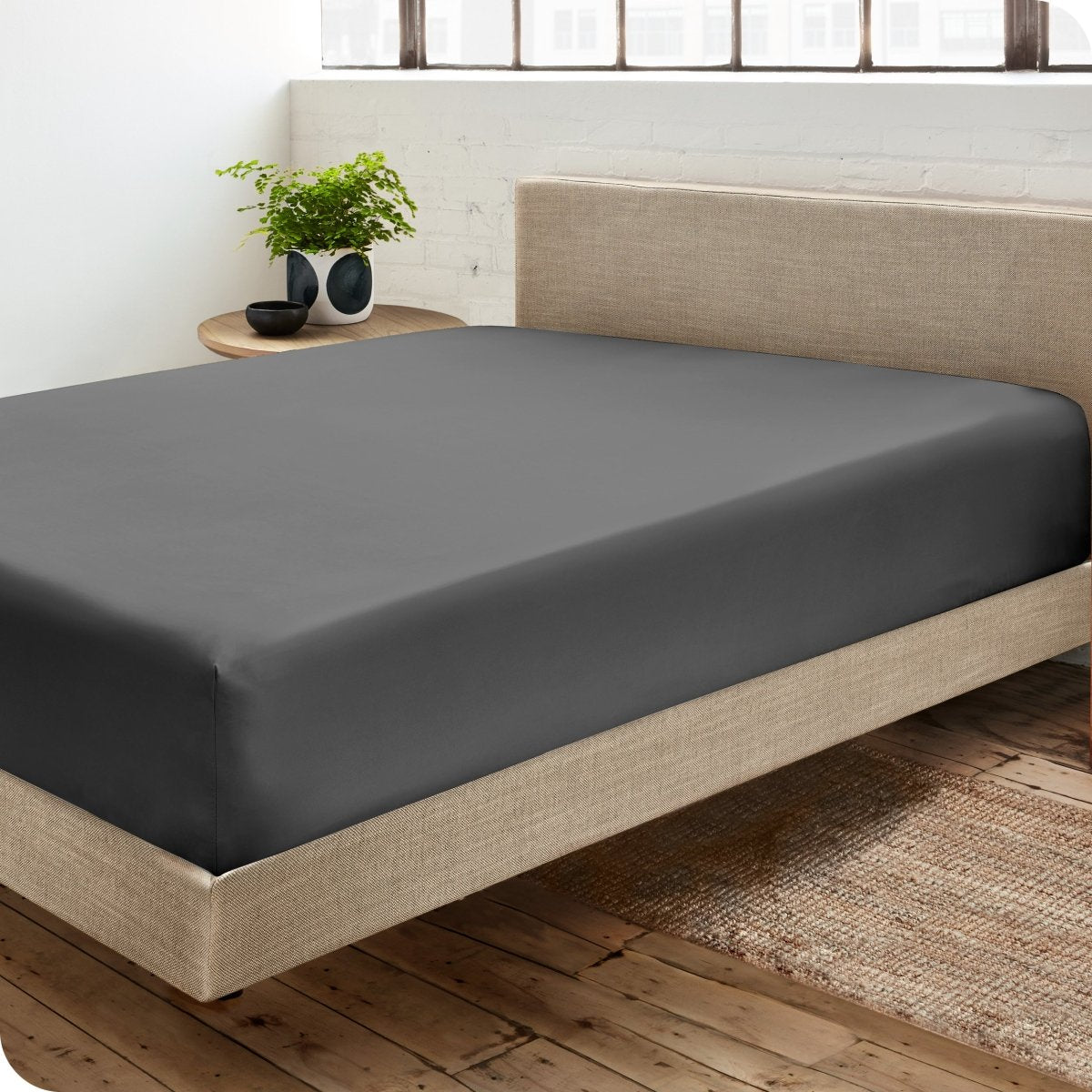 Diagonal view of modern bedroom with a sateen fitted sheet on the bed