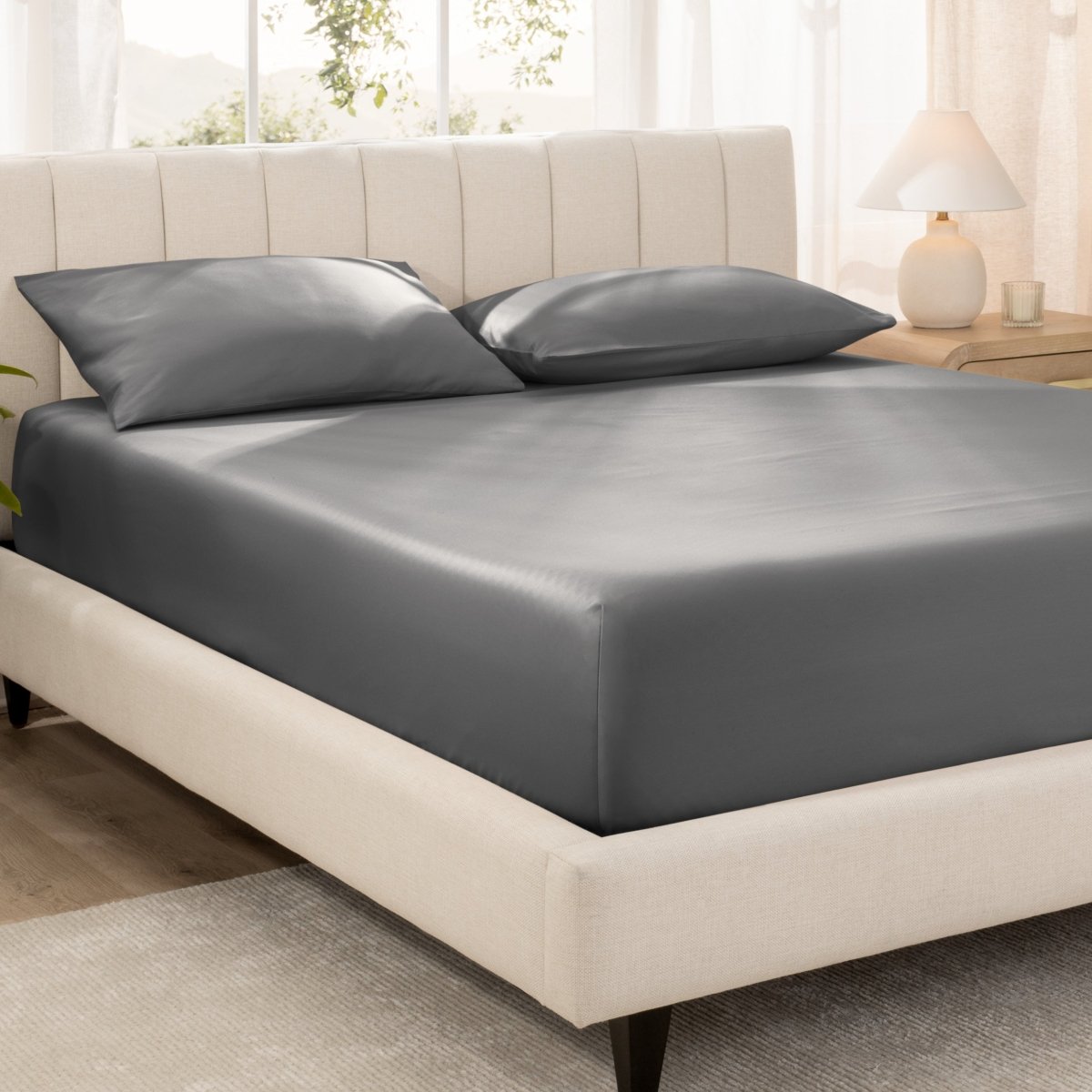 Bed with fitted sheet and pillowcases in a bright room.