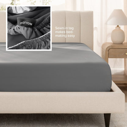 Sateen fitted sheet on a bed with a close-up of a sewn-in tag, set in a bedroom.