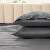 Two pillows stacked on a bed with a beige headboard.